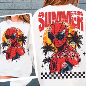 May include: White t-shirt with a graphic of Spiderman wearing sunglasses and a palm tree background. The text "Summer Vibes" is printed in red and black with a checkered pattern at the bottom. The text "Do Not Copy" is printed in small white letters on the graphic.