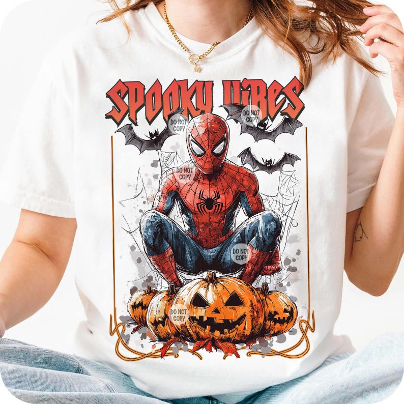 K&ouml;nnte beinhalten: Wei&szlig;es T-Shirt mit einem Spiderman-Motiv und dem Text "Spooky Vibes". Das Design beinhaltet Flederm&auml;use, Spinnweben und Halloween-K&uuml;rbisse, wodurch ein Halloween-Thema entsteht. Spiderman hockt auf den K&uuml;rbissen.