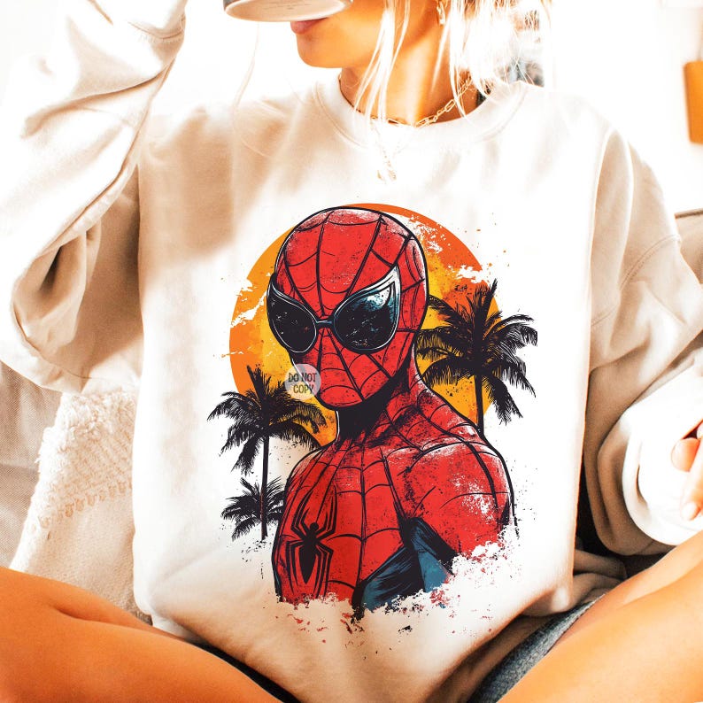 May include: A white sweatshirt with a graphic print of Spider-Man wearing sunglasses and standing in front of a sunset with palm trees. The graphic is in a vintage style.