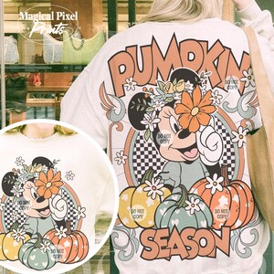 May include: A white sweatshirt with a colorful graphic design featuring a cartoon mouse with a flower crown, pumpkins, and the text "Pumpkin Season".