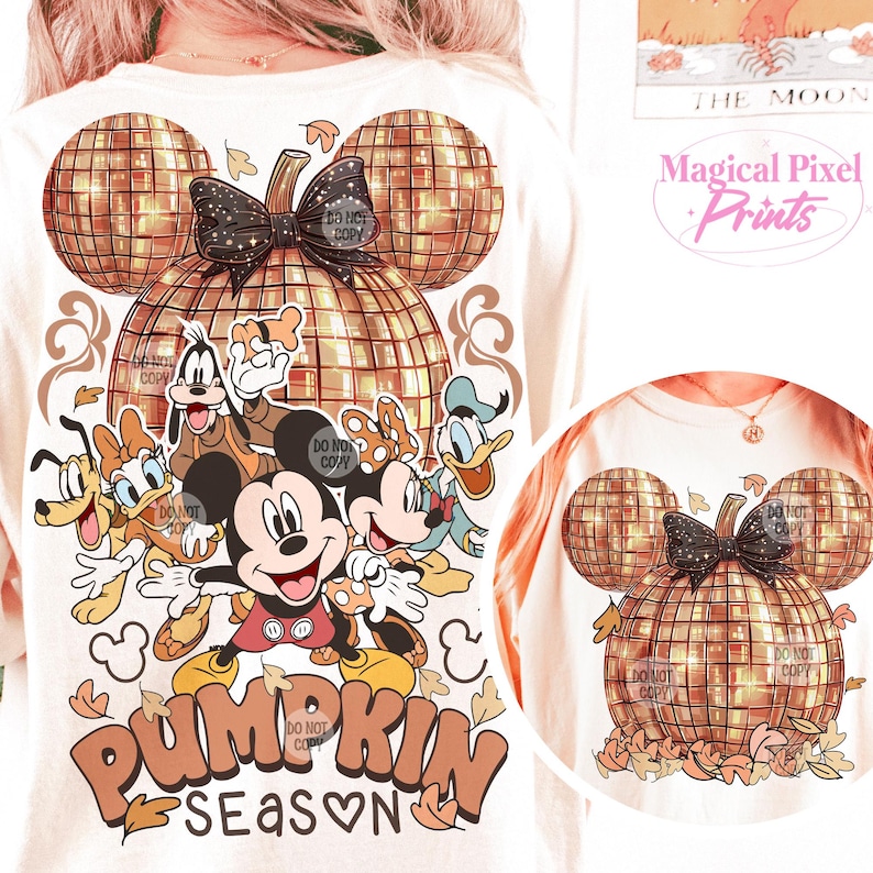 K&ouml;nnte beinhalten: Ein wei&szlig;es T-Shirt mit einem goldenen Glitzer-K&uuml;rbis-Design. Der K&uuml;rbis ist in Form von Mickey-Maus-Ohren und hat eine schwarze Schleife. Das Shirt zeigt auch eine Gruppe von Disney-Charakteren, darunter Mickey Mouse, Minnie Mouse, Donald Duck, Goofy und Pluto. Der Text "Pumpkin Season" ist in orangefarbenen und braunen Buchstaben unter den Figuren geschrieben.