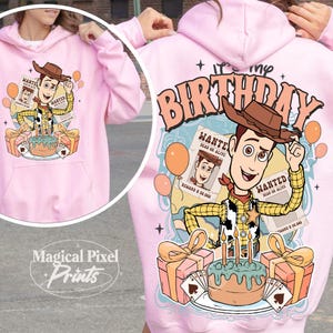 May include: Pink hoodie with a cartoon image of Woody from Toy Story. The image includes a birthday cake, presents, and balloons. The text "It's my Birthday" is printed on the hoodie.