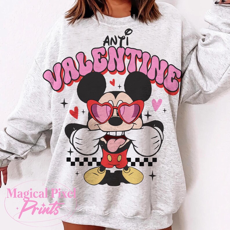 Pu&ograve; includere: Una felpa grigia con una grafica rosa e bianca di Topolino che indossa occhiali a forma di cuore e il testo "Anti Valentine".