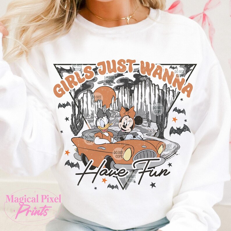 May include: White sweatshirt featuring a graphic print of Mickey Mouse and Daisy Duck driving a vintage car through a spooky forest. The text "Girls Just Wanna Have Fun" is printed in a retro font.