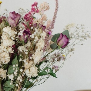 May include: A bouquet of dried flowers in shades of pink, white, and green. The bouquet includes roses, baby's breath, and other dried flowers.