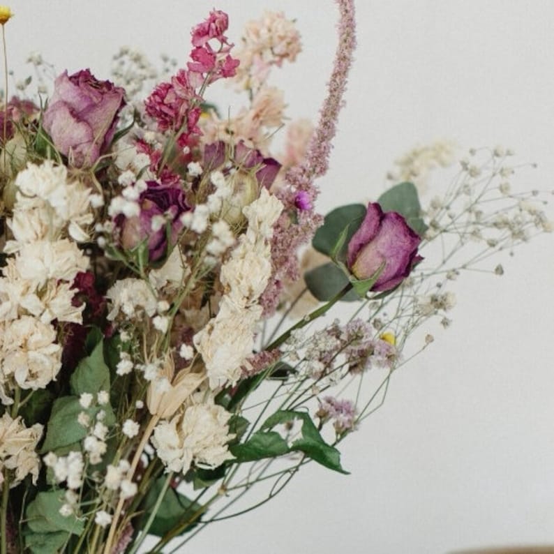 May include: A bouquet of dried flowers in shades of pink, white, and green. The bouquet includes roses, baby's breath, and other dried flowers.