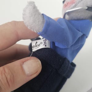 Puede incluir: Un rat&oacute;n de peluche gris con camisa azul, pantalones azul marino y gafas. El rat&oacute;n tiene la nariz y las mejillas rosas. Una etiqueta dice "alee&reg; ee.com" y "2016". El rat&oacute;n es un juguete de peluche con tem&aacute;tica navide&ntilde;a.