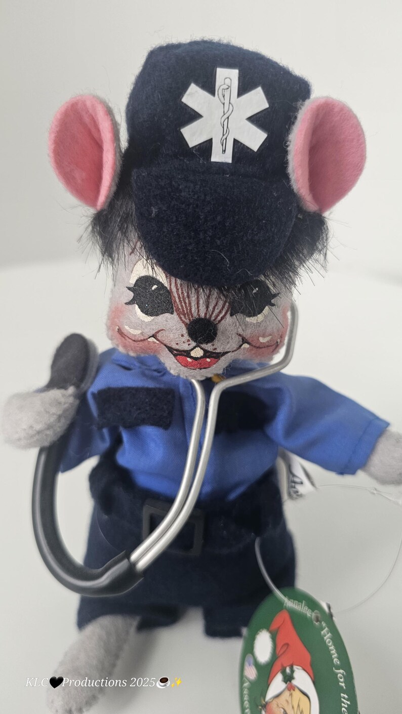 Puede incluir: Un peluche de rat&oacute;n vestido de param&eacute;dico, con uniforme azul y gorro azul marino con un s&iacute;mbolo m&eacute;dico blanco. El rat&oacute;n tiene orejas rosas y sostiene un estetoscopio. Un art&iacute;culo de novedad.