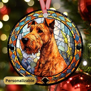 May include: A round, glass Christmas ornament featuring a stained glass design of an Irish Terrier dog. The ornament is surrounded by a colorful, geometric pattern. The dog is brown and red with a white chest and a black nose. The ornament is personalized.