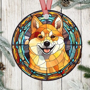 May include: A stained glass ornament featuring a Shiba Inu dog with a colorful background. The dog is depicted in a circular frame with a stained glass design.