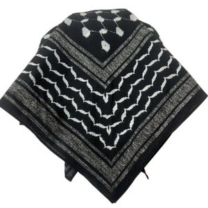 Puede incluir: Bandana estampada en blanco y negro. La bufanda cuadrada presenta un diseño de zigzag blanco repetido sobre un fondo negro, con un borde gris. La bandana está doblada en forma de triángulo.