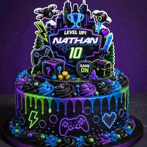 Puede incluir: Una tarta redonda, glaseada en negro, con detalles en verde neón, azul y morado. La tarta está decorada con adornos temáticos de juegos, incluyendo un paisaje urbano, un mando y el texto "LEVEL UP! NATHAN 10".