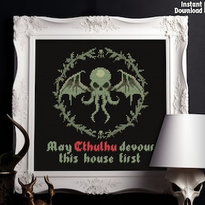 Pode incluir: Um padrão de ponto cruz com um monstro Cthulhu verde com tentáculos e asas, rodeado por uma coroa de folhas. O texto "May Cthulhu devour this house first" está escrito abaixo do monstro.