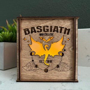 May include: A wooden box with a dragon design and the text "Basgiath War College" and "Fly... or Die".