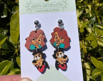 May include: A pair of wooden earrings featuring the characters of the Disney movie, 'The Fox and the Hound'. The earrings are made of wood and feature a painted image of Tod the fox and Copper the hound. The earrings are attached to silver posts.