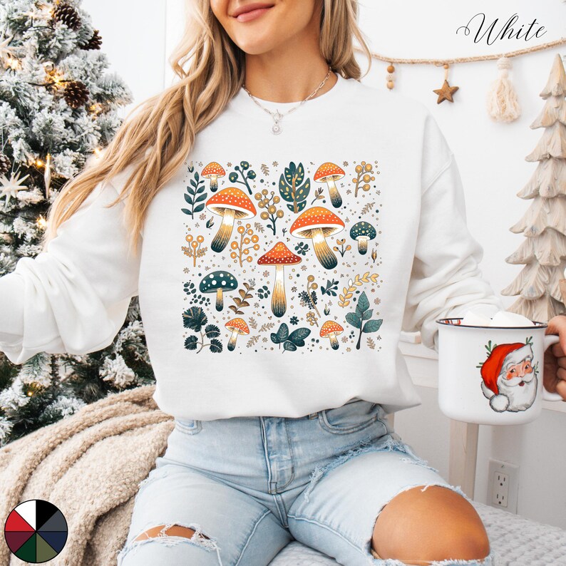 May include: White sweatshirt with a colorful mushroom and leaf pattern. The design features orange, yellow, green, and brown mushrooms with green leaves and stems.