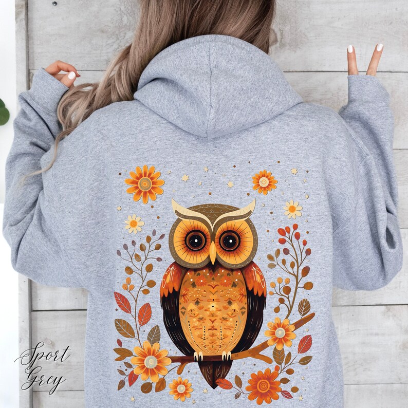 May include: A gray hoodie with a colorful owl design on the back. The owl is surrounded by flowers and leaves in shades of orange, yellow, and brown.