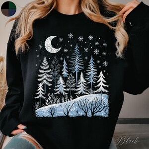May include: Black sweatshirt with a winter scene design featuring a crescent moon, snowflakes, and a forest of blue trees.