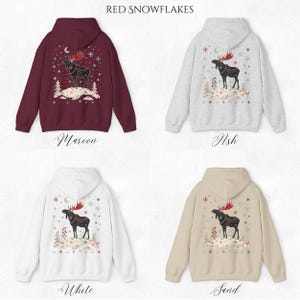 May include: Maroon, ash, white, and sand-colored hoodies with a festive design. Each hoodie features a black moose with red antlers, standing on a snowy hill, surrounded by snowflakes and trees. The text "RED SNOWFLAKES" is at the top.
