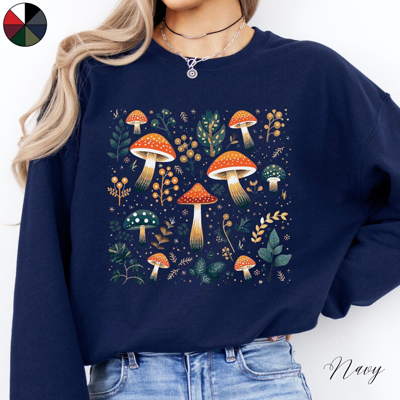 May include: Navy blue sweatshirt with a graphic of colorful mushrooms and leaves. The text "Shroom Queens" is printed on the front of the sweatshirt.