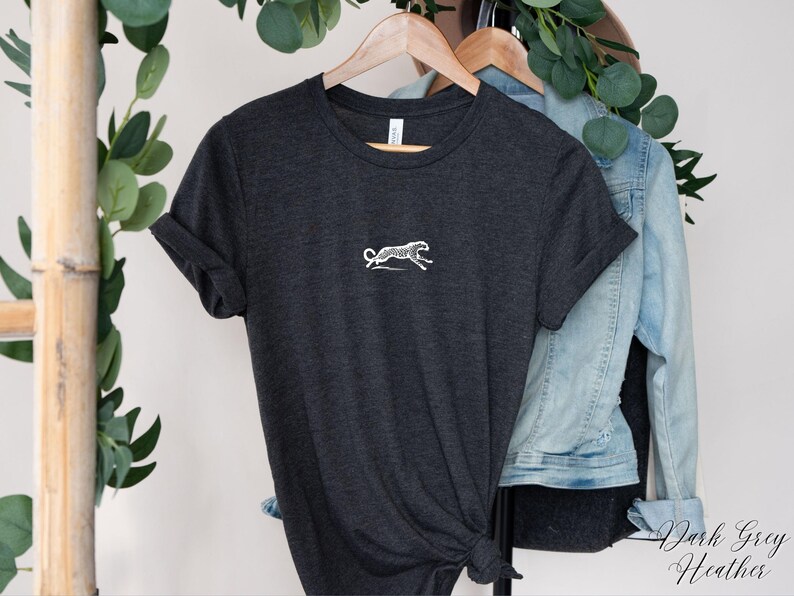 May include: Dark gray heather t-shirt with a white embroidered cheetah design.