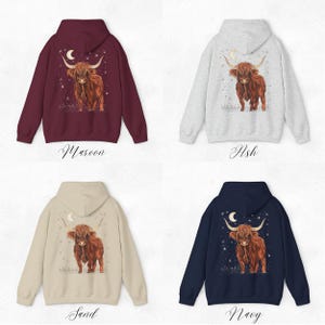 Op de afbeelding: Vier hoodies in bordeauxrood, as, zand en marineblauw. Elke hoodie heeft een aquarel illustratie van een Schotse Hooglandkoe met een maan en sterren. De kleuren zijn met cursieve tekst gelabeld.