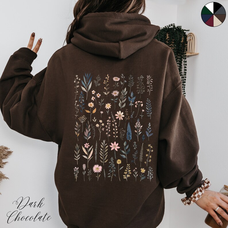 May include: A dark chocolate brown hoodie with a floral print on the back. The print features a variety of flowers and leaves in shades of pink, blue, and green.