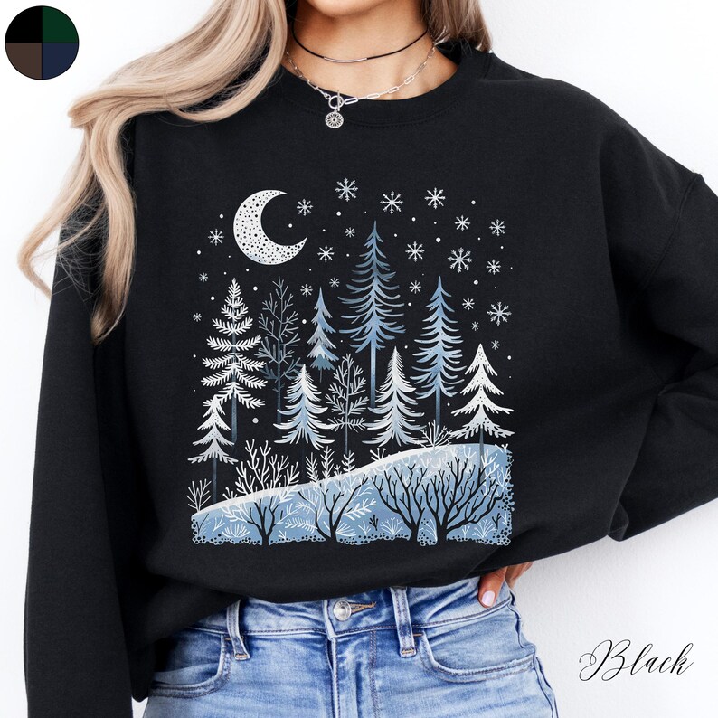 May include: Black sweatshirt with a winter forest scene featuring a crescent moon, snowflakes, and pine trees. The sweatshirt has a relaxed fit and a crew neck.