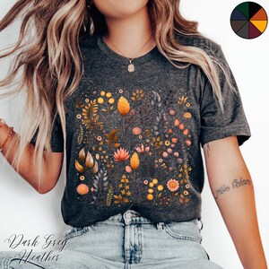 Może przedstawiać: Koszulka w kolorze ciemnoszarym melanż z nadrukiem kwiatowym z ż&oacute;łtymi, pomarańczowymi i r&oacute;żowymi kwiatami na ciemnoszarym tle.