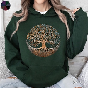 May include: A dark green hooded sweatshirt with a gold and blue tree of life design. The tree has intricate roots and branches with leaves in various shades of gold, blue, and green.