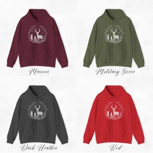 May include: Four hooded sweatshirts in maroon, military green, dark heather, and red. Each sweatshirt features a white graphic of a deer inside a wreath with the text "Maroon", "Military Green", "Dark Heather", and "Red" below each sweatshirt.