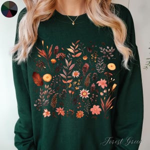 May include: A forest green sweatshirt with a floral print featuring a variety of flowers and leaves in shades of orange, yellow, and pink. The text "Forest Green" is printed on the bottom right corner of the sweatshirt.