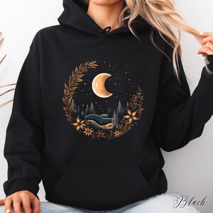 May include: Black hooded sweatshirt with a graphic print of a crescent moon surrounded by a floral wreath and a starry night sky.