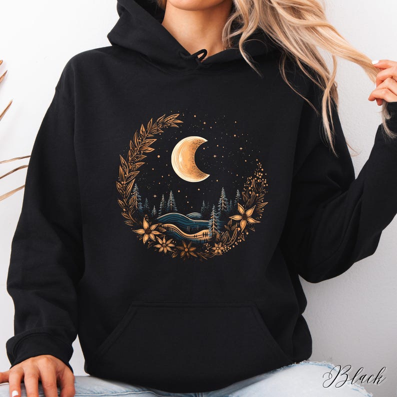 May include: Black hooded sweatshirt with a graphic print of a crescent moon surrounded by a floral wreath and a starry night sky.