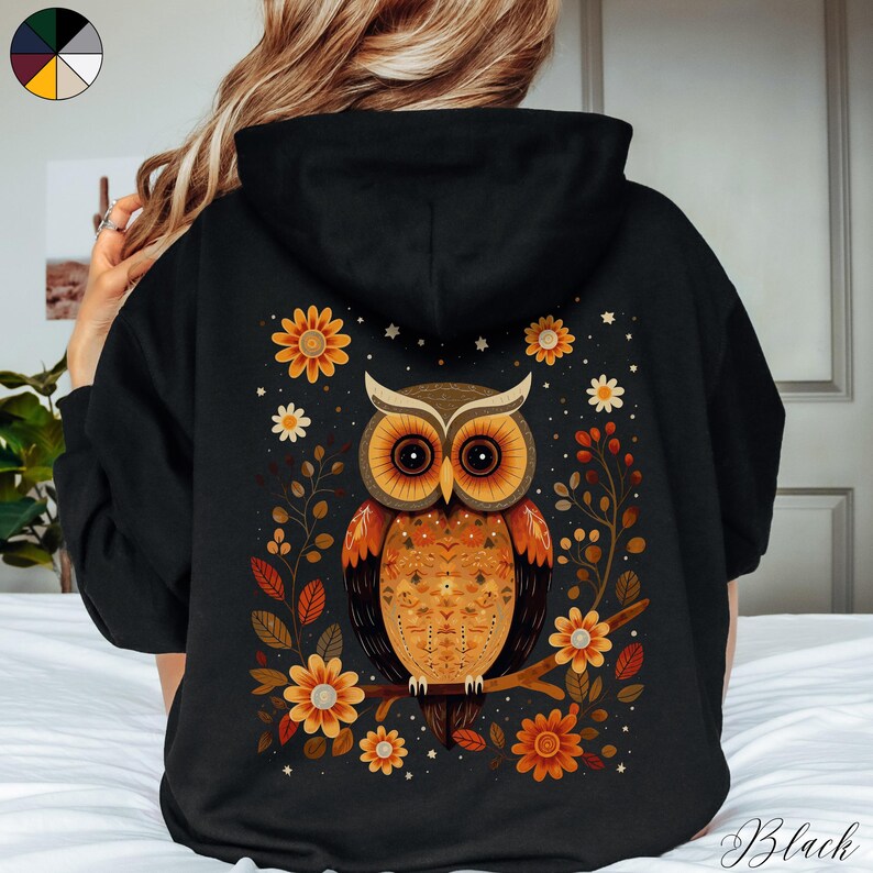 May include: Black hoodie with a colorful owl and floral design on the back. The owl has orange, brown, and yellow feathers. The flowers are yellow, orange, and white.