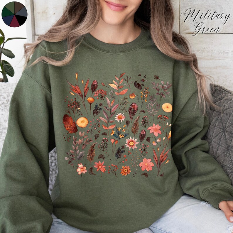 May include: A green sweatshirt with a floral print featuring various shades of orange, pink, and brown. The text "Military Green" is visible in the top right corner of the image.