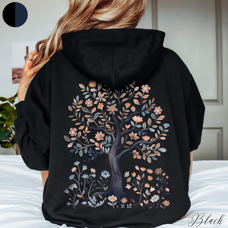 Peut inclure: Sweat-shirt &agrave; capuche noir avec un motif d'arbre floral au dos. L'arbre est de couleur gris fonc&eacute; avec des fleurs roses et bleues.