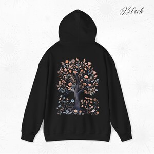 Peut inclure: Sweat-shirt &agrave; capuche noir avec un motif d'arbre floral au dos. L'arbre est de couleur bleu fonc&eacute; avec des fleurs roses et orange.