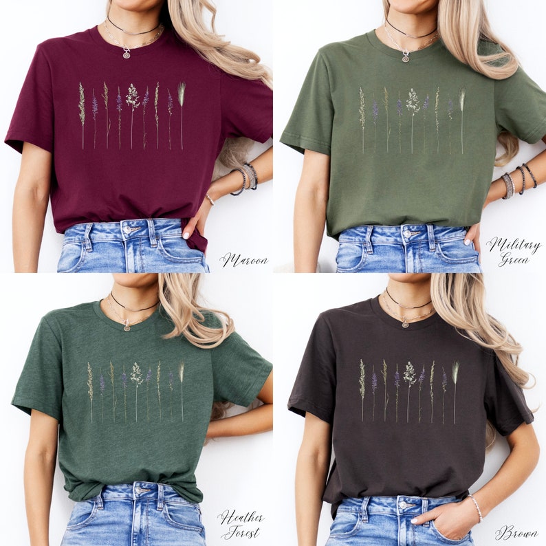 May include: Four t-shirts in different colours featuring a graphic of dried flowers and grasses. The colours are maroon, military green, heather forest, and brown.