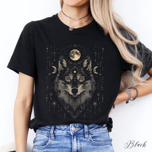 May include: Black t-shirt with a graphic of a wolf's head with a moon and stars in the background.