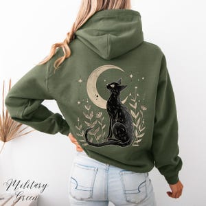 May include: A green hooded sweatshirt with a black cat sitting under a crescent moon with stars. The cat is looking up at the moon. The design is on the back of the sweatshirt.