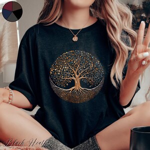 May include: A black t-shirt featuring a gold and blue tree of life design. The tree has intricate roots and branches with leaves in shades of gold and blue.