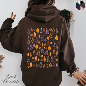 May include: A brown hoodie with a pattern of colorful leaves and flowers on the back. The text "Dark Chocolate" is printed on the bottom left corner of the hoodie.