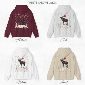 May include: Four hooded sweatshirts in maroon, ash, white, and sand. Each features a moose graphic with red antlers, a crescent moon, and snowflakes. The text "White Snowflakes" is at the top.