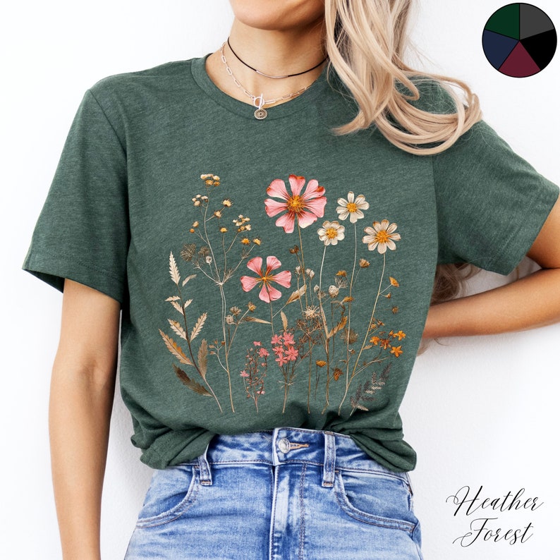 May include: A heather forest green t-shirt with a floral print featuring pink, white, and brown dried flowers.