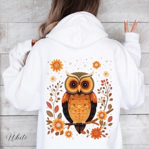 May include: White hooded sweatshirt with a brown and orange owl design on the back. The owl is surrounded by flowers and leaves in shades of orange, yellow, and brown.