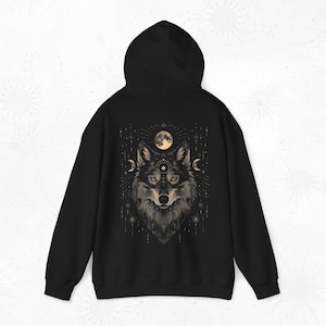 K&ouml;nnte beinhalten: Schwarzer Kapuzenpullover mit einem grafischen Aufdruck eines Wolfskopfes mit einem dritten Auge und einem Vollmond dahinter.