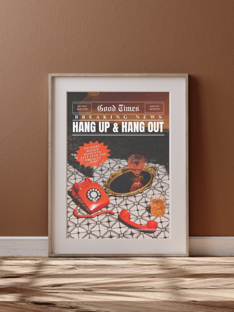 May include: A framed print with a vintage newspaper design featuring the text "Good Times Hottie Edition Breaking News Hang Up & Hang Out" with a red rotary phone and a glass of wine on a tray. The text "No More Missed Moments: Step Into The Present Now!" is in a red circle.