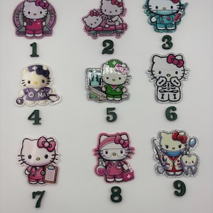 May include: A collection of nine Hello Kitty character charms in various medical and healthcare-related themes. Each charm features a different design, including a nurse, doctor, and patient, with vibrant colors and glitter accents.