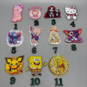 May include: A collection of eleven glittery character charms, including a pink bear, a cartoon pig, Sally and Jack Skellington, Hello Kitty, Stitch, Snoopy, a Gremlin, Pikachu, SpongeBob SquarePants, and Winnie the Pooh.
